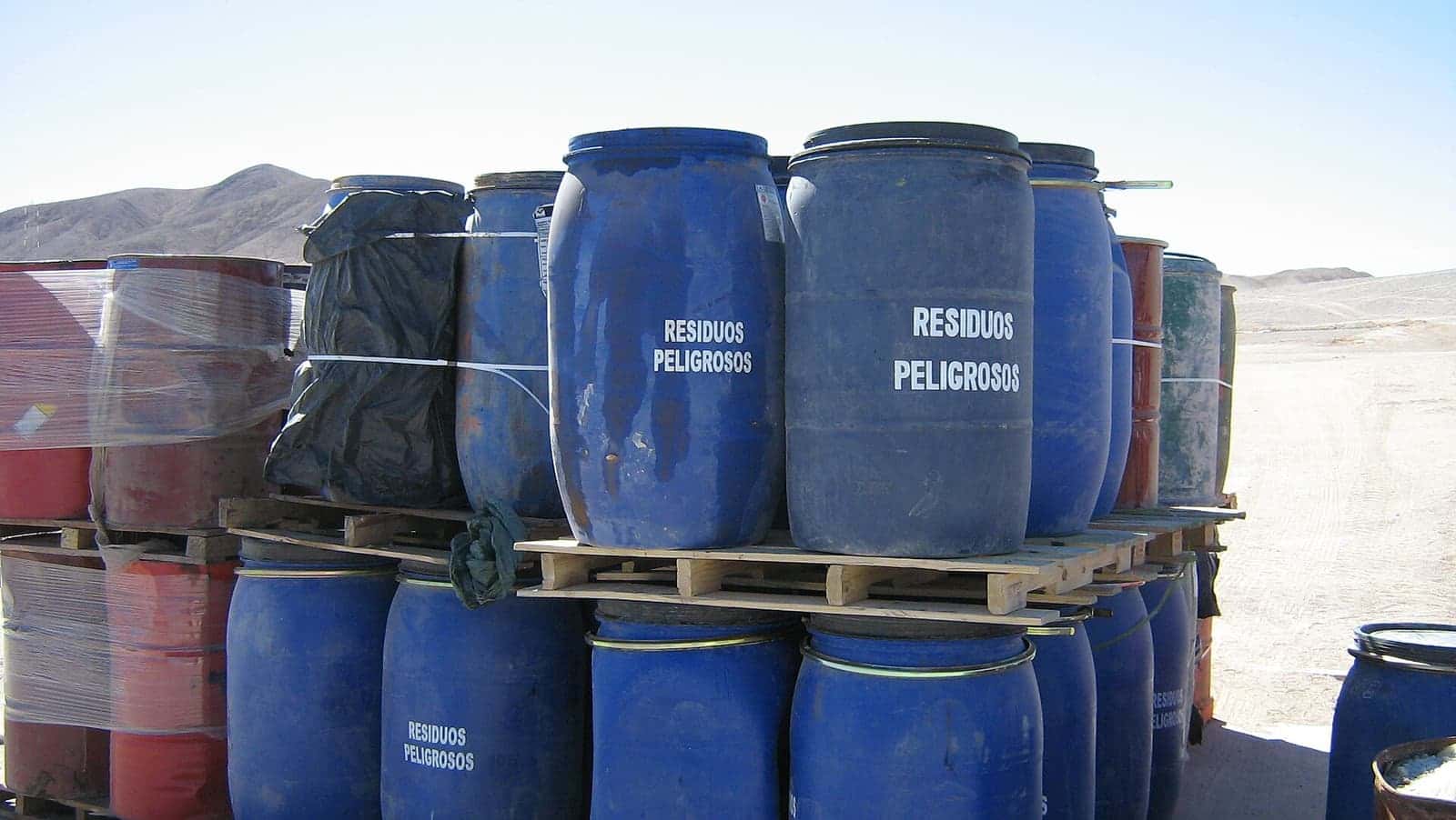 Drum plastik biru berlabel limbah berbahaya disusun di atas palet